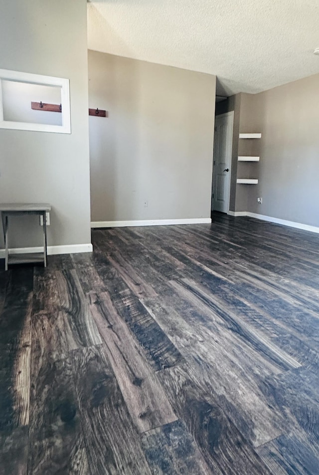 spare room featuring a textured ceiling, baseboards, and wood finished floors