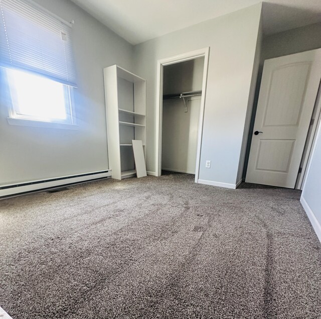 unfurnished bedroom with carpet, a closet, a baseboard heating unit, and baseboards