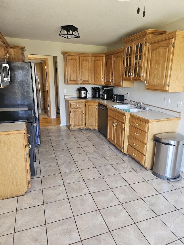 kitchen featuring stove, a sink, black dishwasher, light countertops, and stainless steel microwave