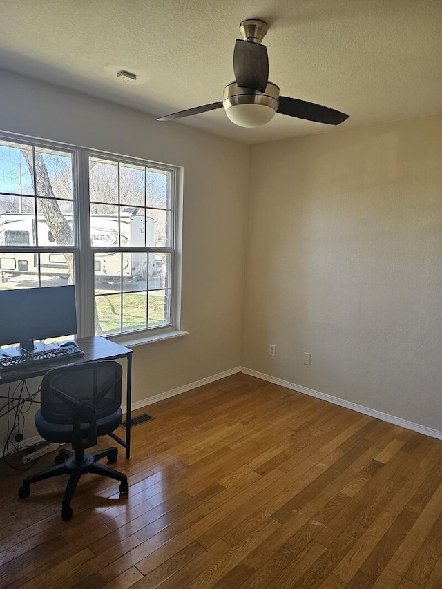 office area with a ceiling fan, a textured ceiling, baseboards, and hardwood / wood-style floors