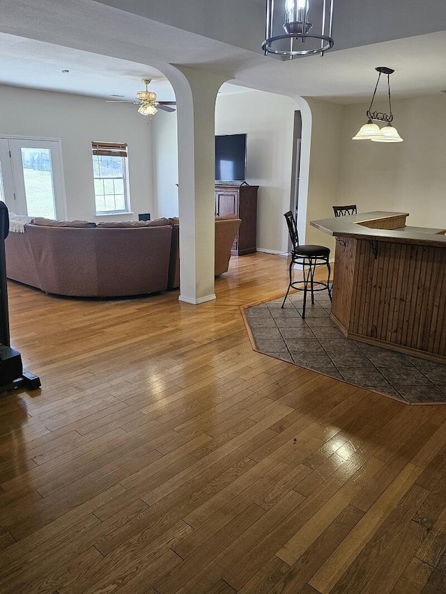 interior space with arched walkways, ceiling fan, baseboards, and hardwood / wood-style flooring