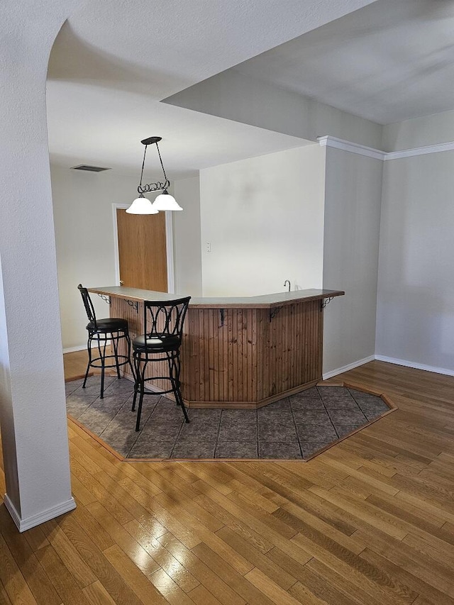 bar featuring arched walkways, visible vents, baseboards, wood-type flooring, and pendant lighting