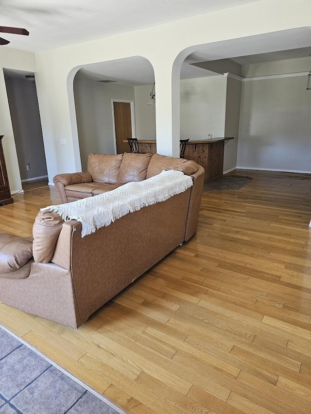 living room with light wood-style flooring, arched walkways, and a ceiling fan