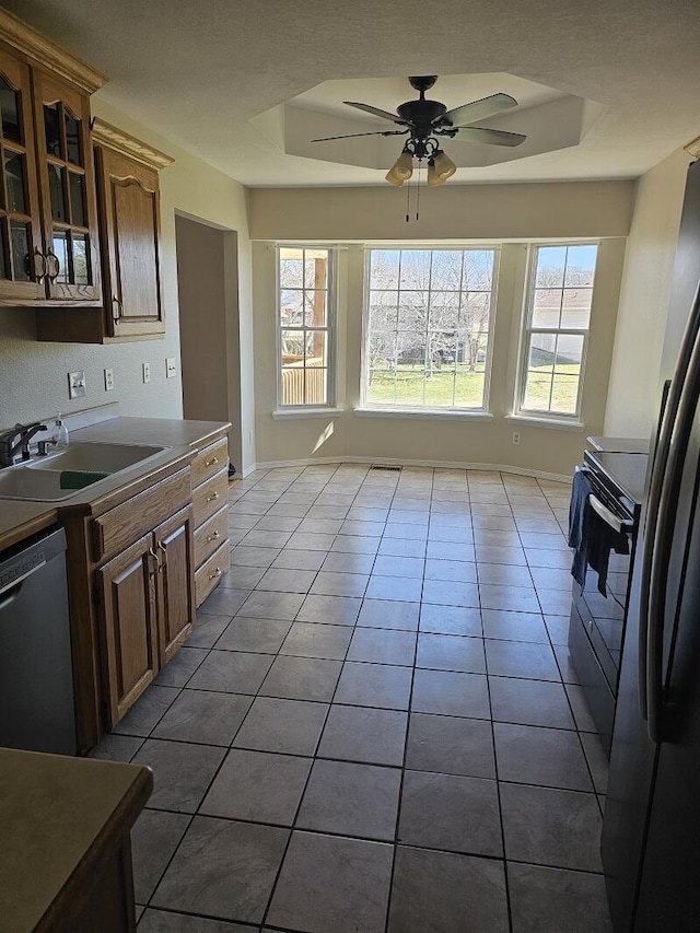 kitchen with a sink, tile patterned floors, dishwasher, a raised ceiling, and glass insert cabinets