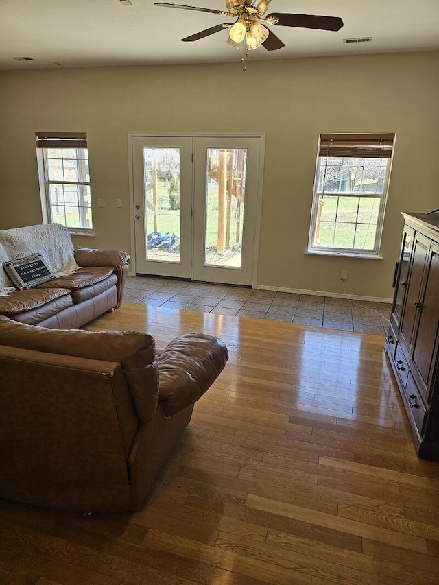 living area featuring visible vents, ceiling fan, baseboards, and wood finished floors