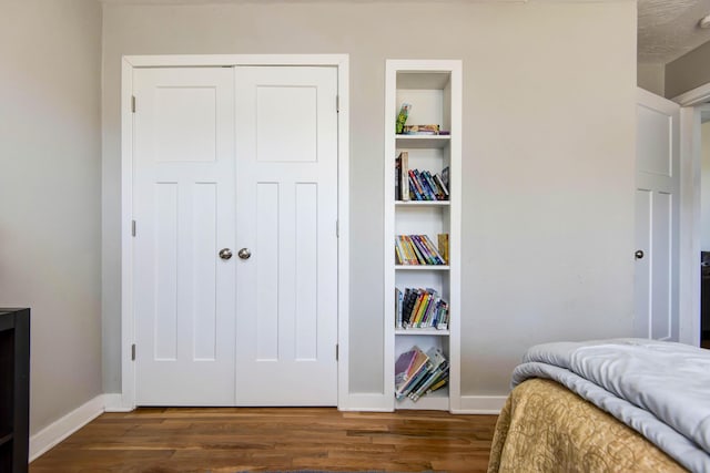 bedroom featuring dark wood-type flooring, a closet, and baseboards