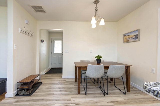 dining area with baseboards, visible vents, a notable chandelier, and light wood finished floors