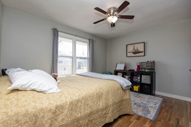 bedroom with a textured ceiling, wood finished floors, a ceiling fan, and baseboards