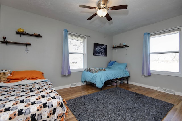 bedroom featuring wood finished floors, visible vents, and multiple windows