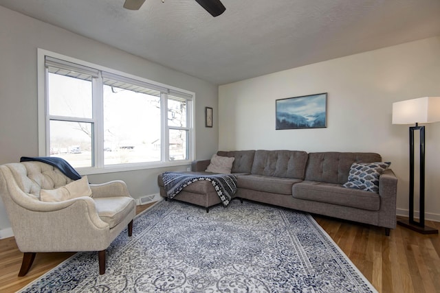 living area featuring baseboards, a textured ceiling, visible vents, and wood finished floors