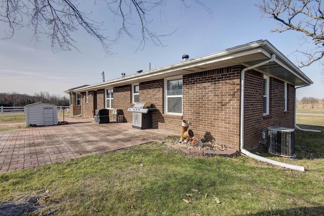 rear view of property featuring a patio, cooling unit, a storage shed, brick siding, and an outdoor structure