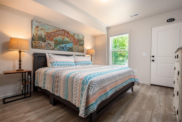 bedroom featuring wood finished floors, visible vents, and baseboards