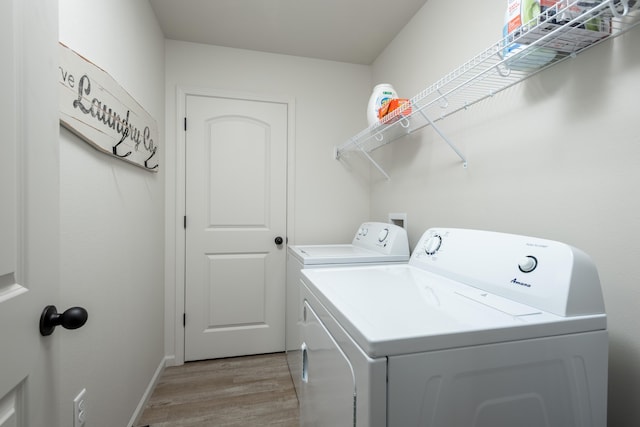 laundry area featuring laundry area, light wood-type flooring, washing machine and dryer, and baseboards