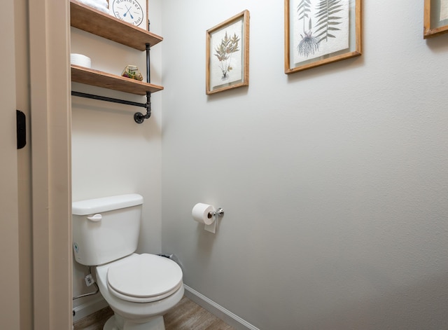 bathroom with wood finished floors, toilet, and baseboards