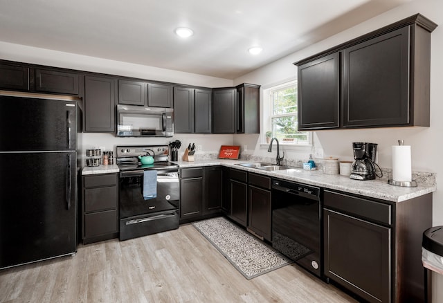 kitchen with light stone counters, recessed lighting, a sink, light wood-style floors, and black appliances