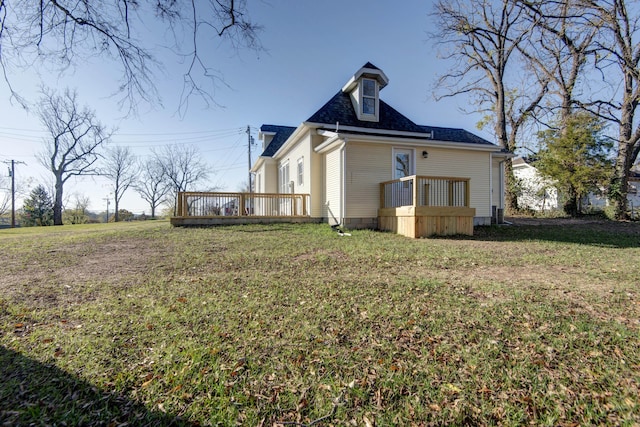 back of property with a deck and a lawn