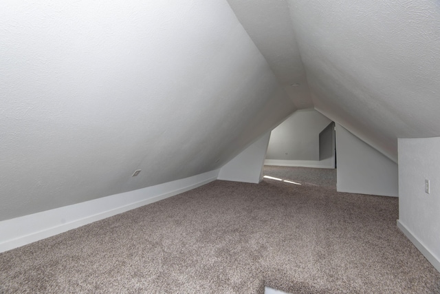 bonus room featuring vaulted ceiling, a textured ceiling, carpet flooring, and baseboards