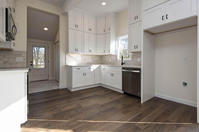 kitchen featuring dark wood-style flooring, light countertops, stainless steel dishwasher, white cabinets, and baseboards