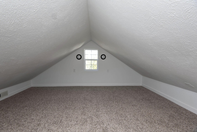 bonus room with carpet floors, baseboards, vaulted ceiling, and a textured ceiling