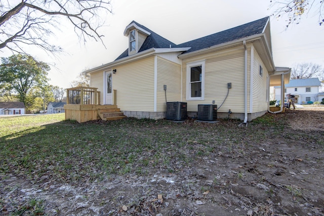 back of house featuring central AC unit and roof with shingles