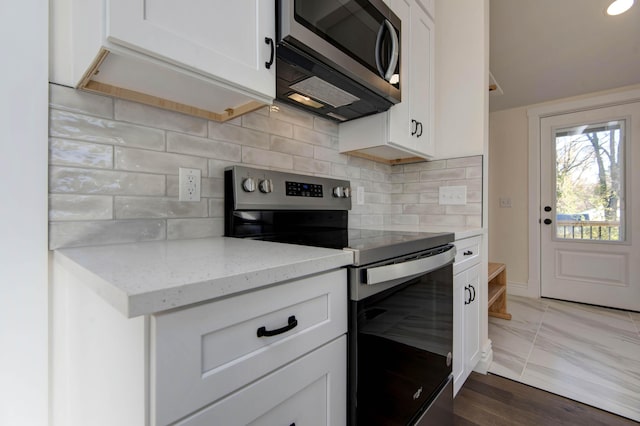 kitchen with stainless steel appliances, backsplash, light stone countertops, and white cabinets