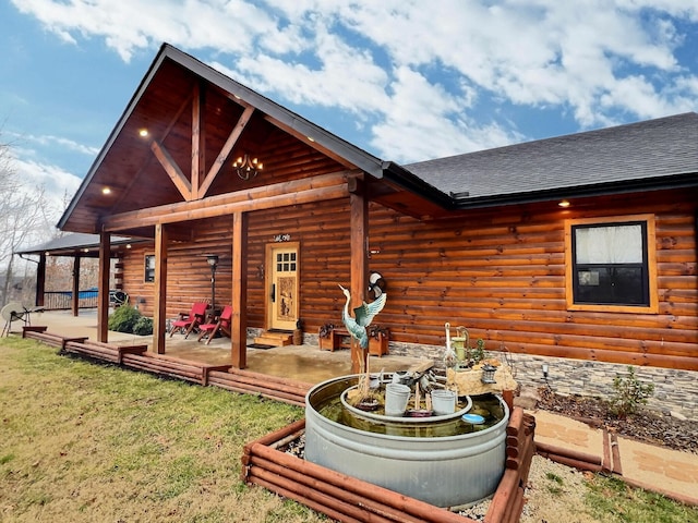 rear view of house featuring a patio area, roof with shingles, and a lawn