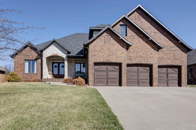 french country inspired facade with brick siding, a shingled roof, driveway, french doors, and a front yard