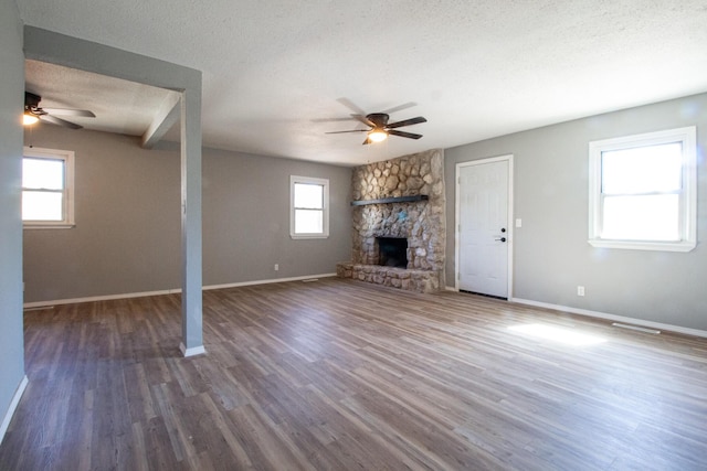 unfurnished living room featuring a textured ceiling, a fireplace, wood finished floors, a ceiling fan, and baseboards