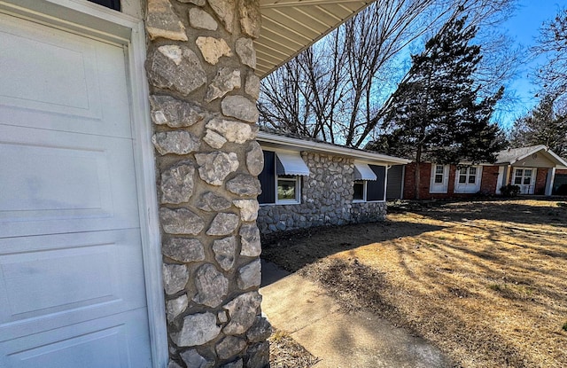 view of side of property featuring a garage and stone siding