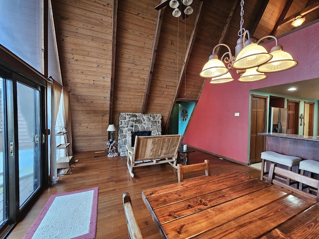 dining area featuring plenty of natural light, a fireplace, beamed ceiling, and wood finished floors