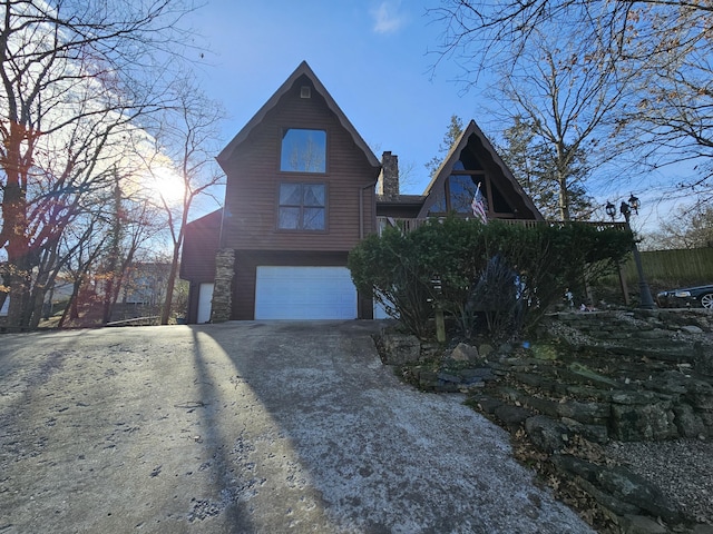 view of side of home with aphalt driveway, a chimney, and a garage