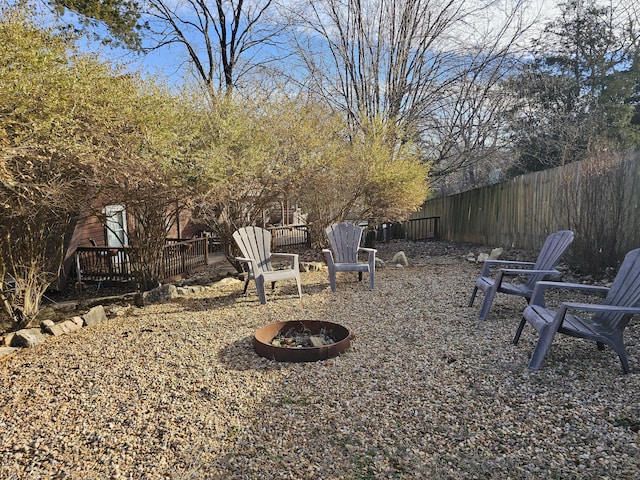 view of yard with a fire pit, a deck, and fence