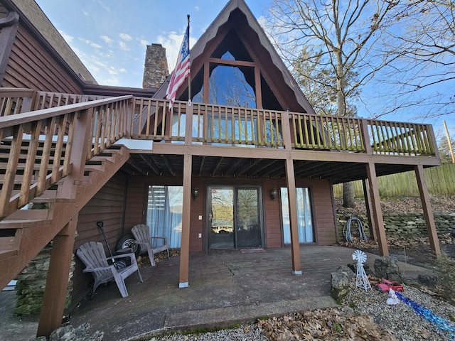 rear view of property featuring stairs, a patio, a deck, and a chimney