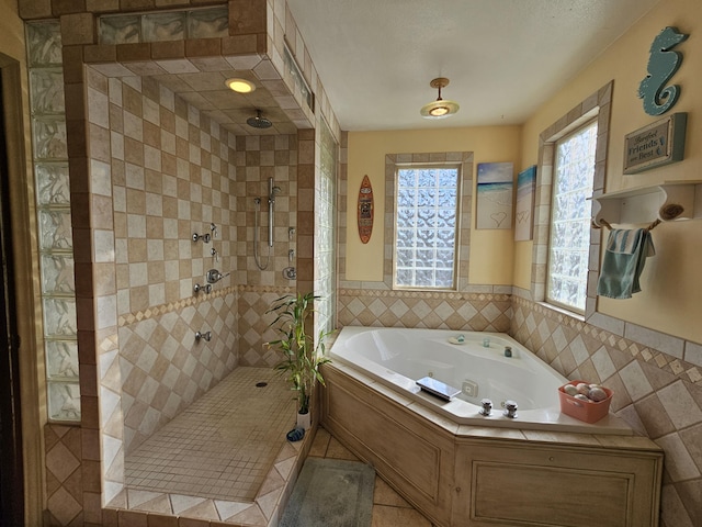 bathroom featuring tile walls, wainscoting, a walk in shower, tile patterned flooring, and a whirlpool tub