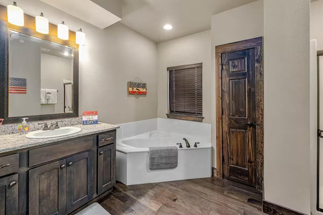 full bathroom with a garden tub, wood finished floors, and vanity