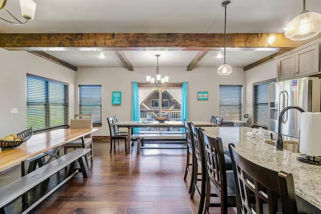 kitchen featuring light stone countertops, dark wood-style floors, an inviting chandelier, stainless steel fridge, and pendant lighting