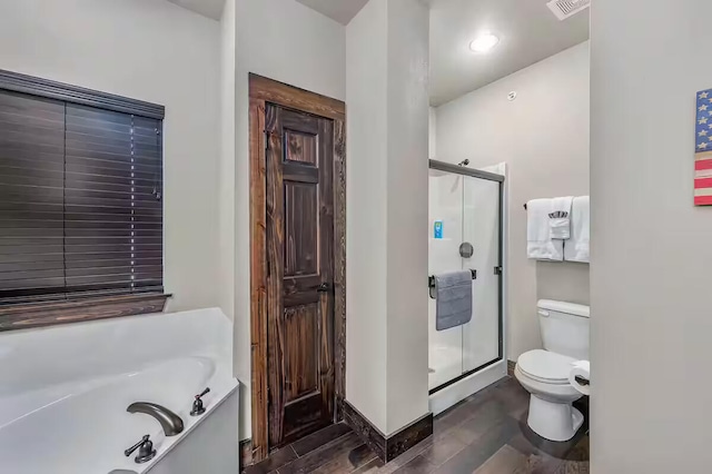 full bathroom with toilet, wood finished floors, visible vents, a bath, and a stall shower