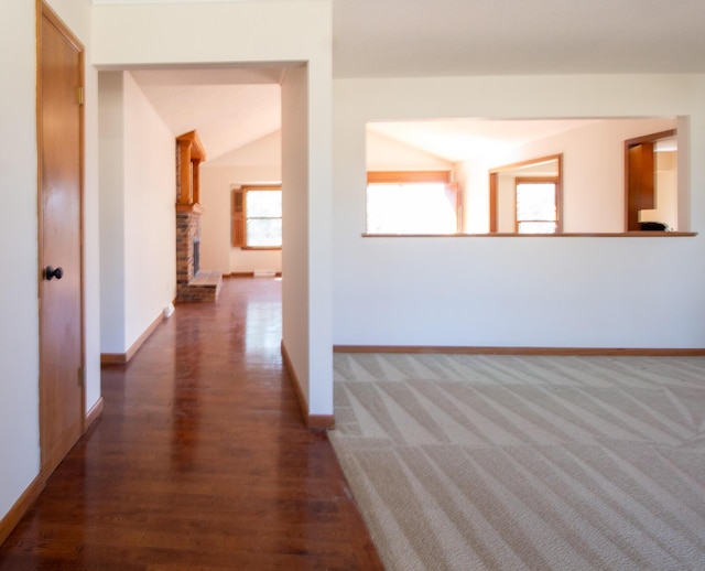 interior space featuring vaulted ceiling, wood finished floors, and baseboards