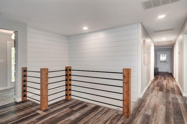 hall with recessed lighting, visible vents, wooden walls, wood finished floors, and baseboards