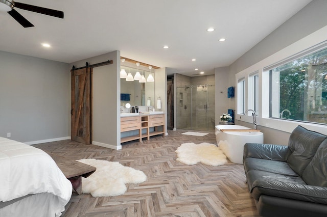 bedroom with a barn door, recessed lighting, a ceiling fan, baseboards, and ensuite bath