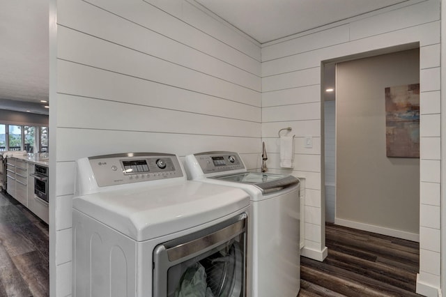 washroom featuring laundry area, baseboards, dark wood-type flooring, and independent washer and dryer