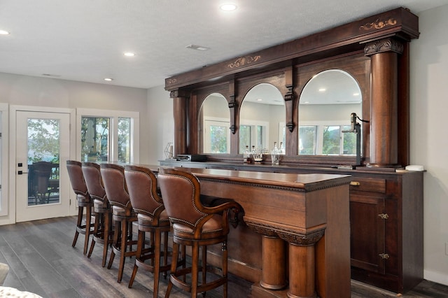 bar featuring a bar, dark wood-type flooring, and recessed lighting