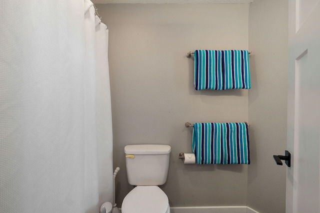 full bathroom with curtained shower, toilet, and baseboards