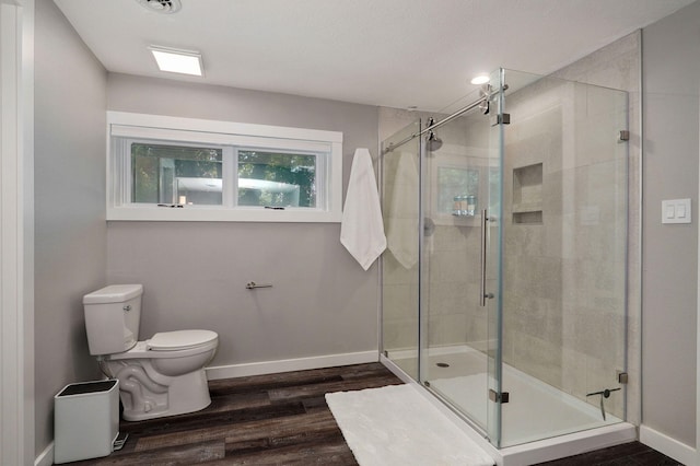 bathroom with a shower stall, toilet, and baseboards