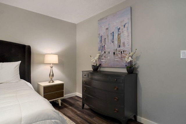 bedroom with dark wood-type flooring and baseboards