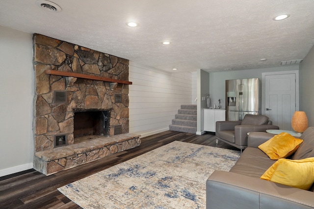 living room with visible vents, wood finished floors, and a stone fireplace