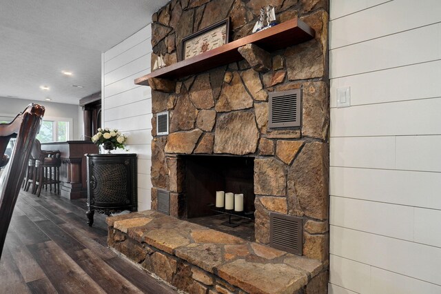 room details with visible vents, wood finished floors, a textured ceiling, wood walls, and a fireplace