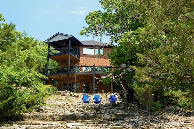 rear view of house featuring stairs, brick siding, a balcony, and a ceiling fan