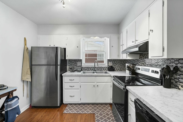 kitchen featuring decorative backsplash, dark wood-style floors, appliances with stainless steel finishes, under cabinet range hood, and a sink