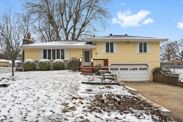 tri-level home with a garage, driveway, and a chimney